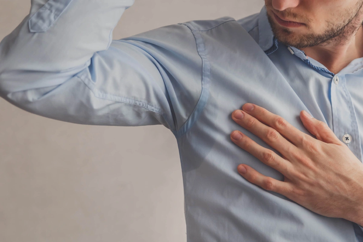 Man checking underarm sweat stains, highlighting the need for sweat gland treatment in Roseville, CA to reduce excessive sweating and odor.